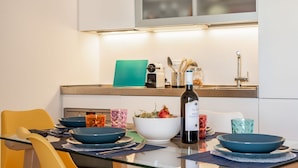 Une cuisine moderne avec une table à manger dressée pour deux personnes, une bouteille de vin et divers ustensiles de cuisine.