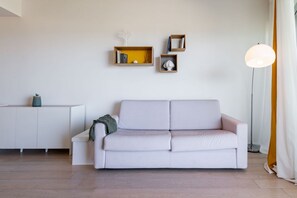 Un salon moderne avec un canapé blanc, un meuble blanc et un lampadaire.