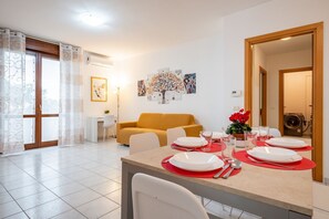 Un comedor con una mesa dispuesta para cuatro, un sofá y un cuadro en la pared.