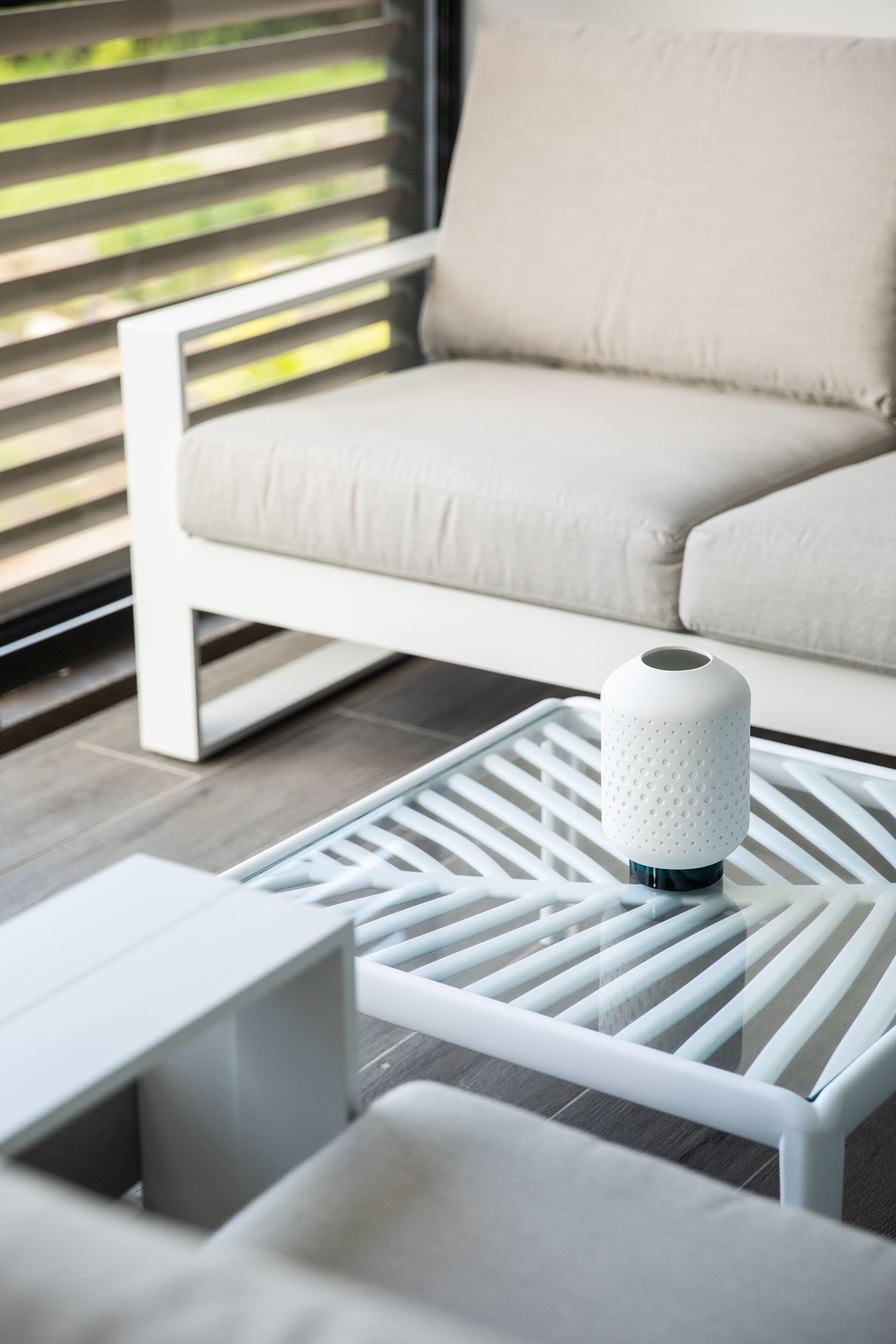 Una sala de estar moderna con un sofá blanco, una mesa de centro blanca de diseño geométrico y una lámpara blanca.