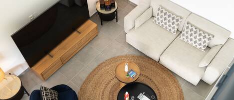 A modern living room with a flat-screen TV, a sofa, a coffee table, and a chair.