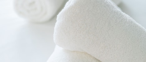 Neatly rolled white towels on a white surface.