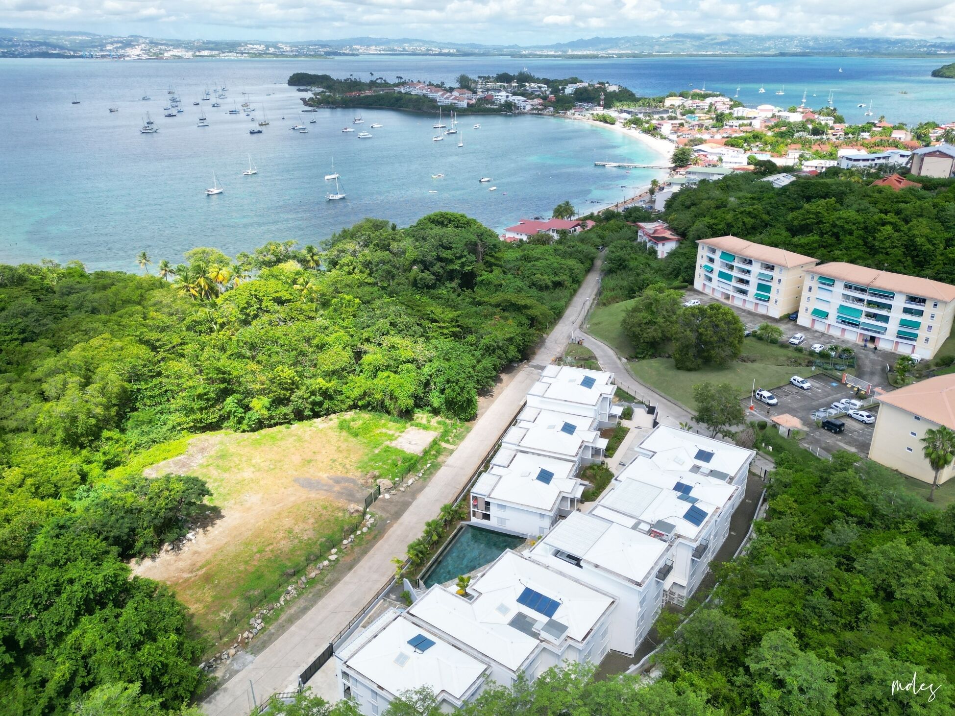 Une zone côtière dotée d’un port de plaisance, d’une végétation luxuriante et d’un immeuble résidentiel comprenant plusieurs logements.
