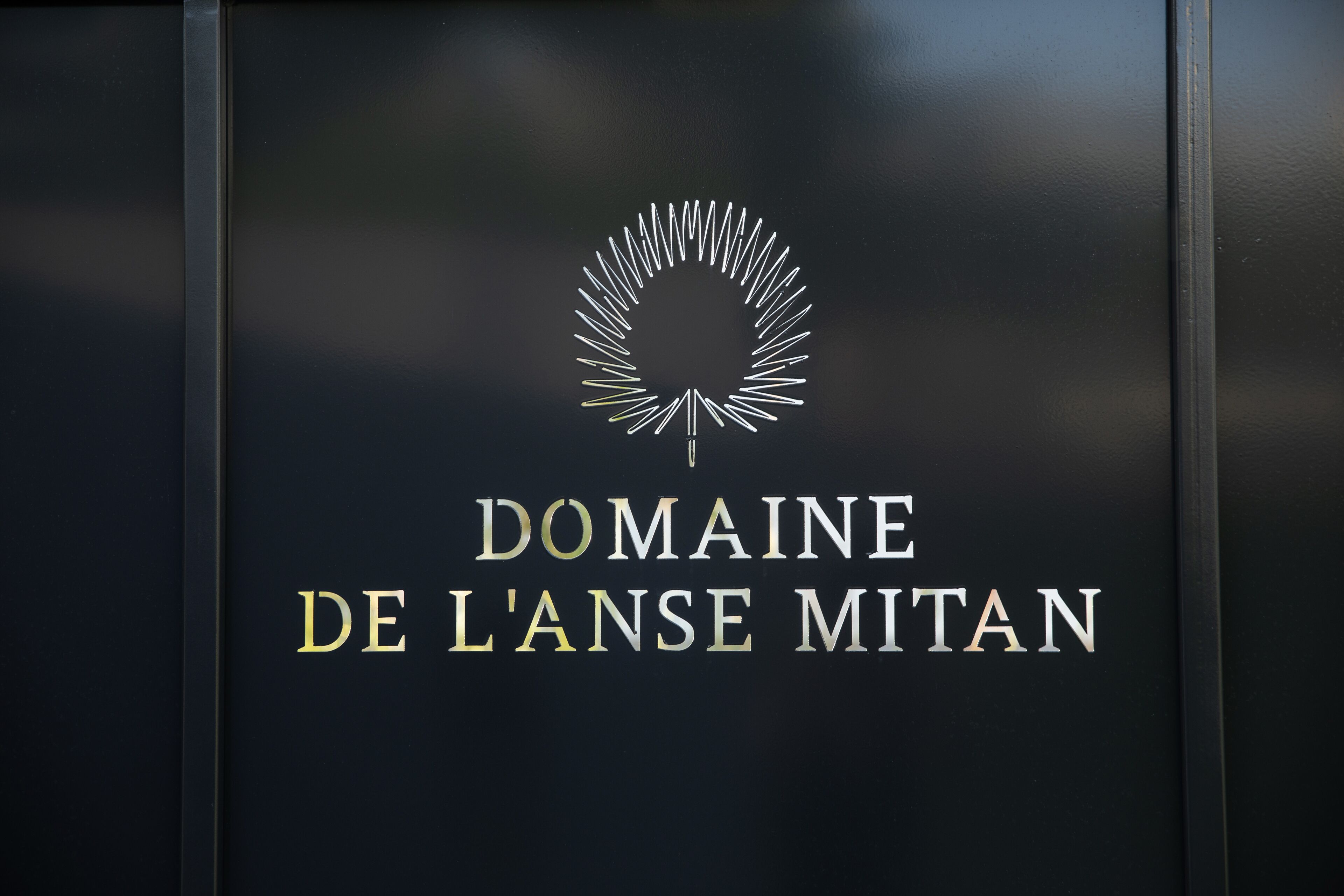 Un logotipo con el texto 'DOMAINE DE L'ANSE MITAN' sobre un fondo oscuro.