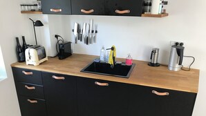 A compact kitchen with a black countertop, a sink, and various appliances.