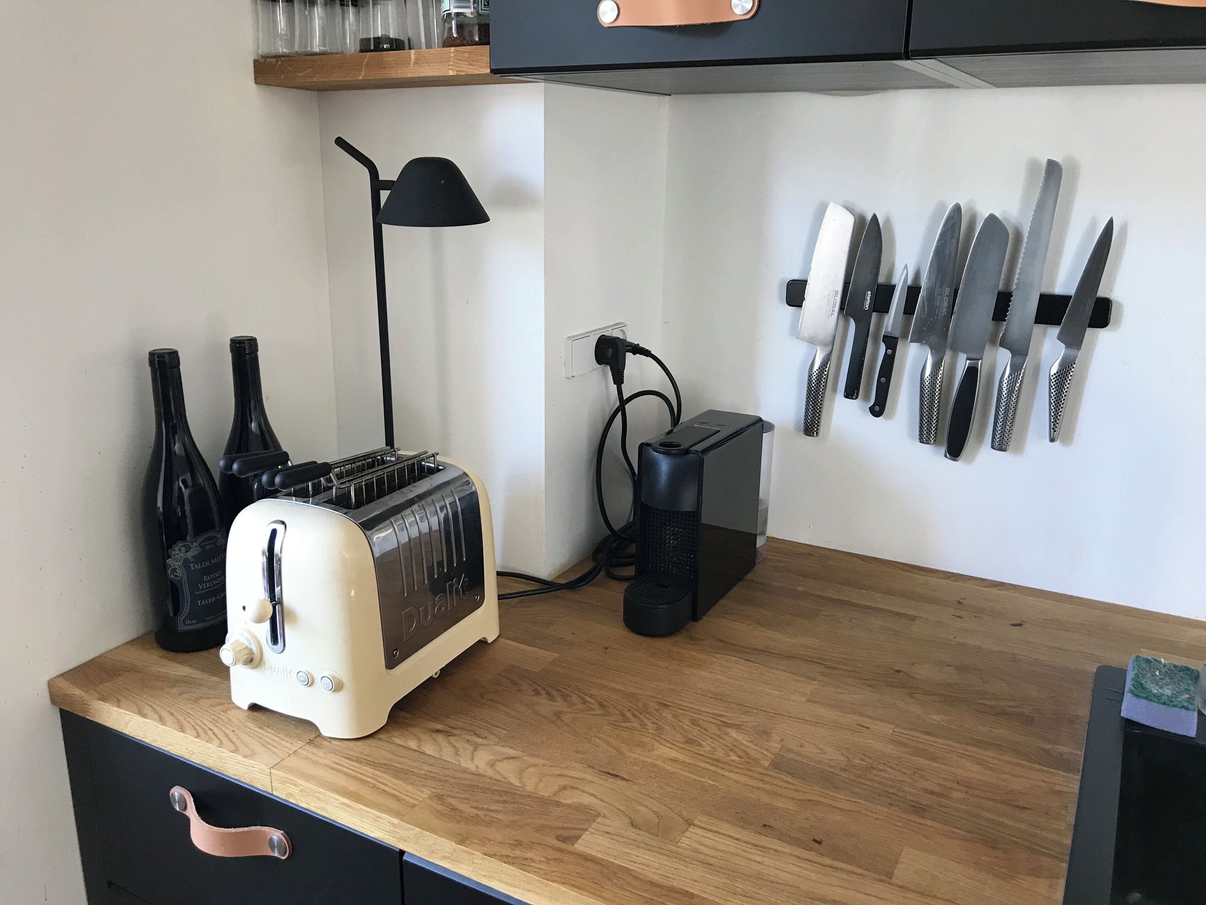 Une cuisine avec un plan de travail en bois, un grille-pain, une lampe et un porte-couteaux.