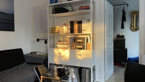 A compact living space with a built-in bookshelf, a small desk with a laptop, and a bed.
