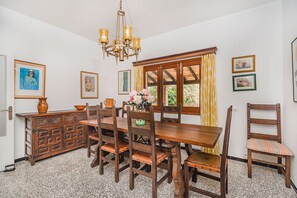 Un coin repas avec une table et des chaises en bois, un lustre et des œuvres d’art encadrées accrochées aux murs.