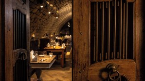 Un interior rústico con techo de piedra, puerta de madera con manija de metal, y un área de comedor con mesas y sillas.