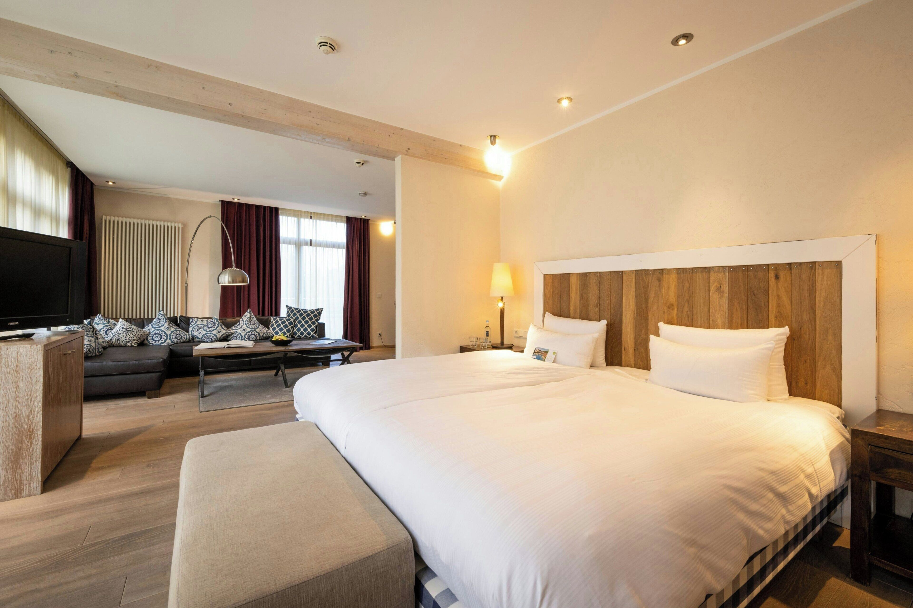 A hotel room with a large bed, a sofa, a TV, and a desk.