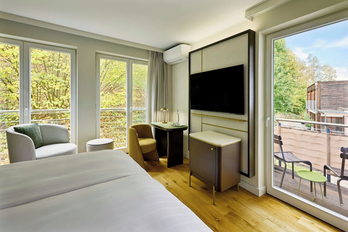 Quarto de hotel moderno com uma cama grande, uma escrivaninha, uma cadeira e uma televisão.