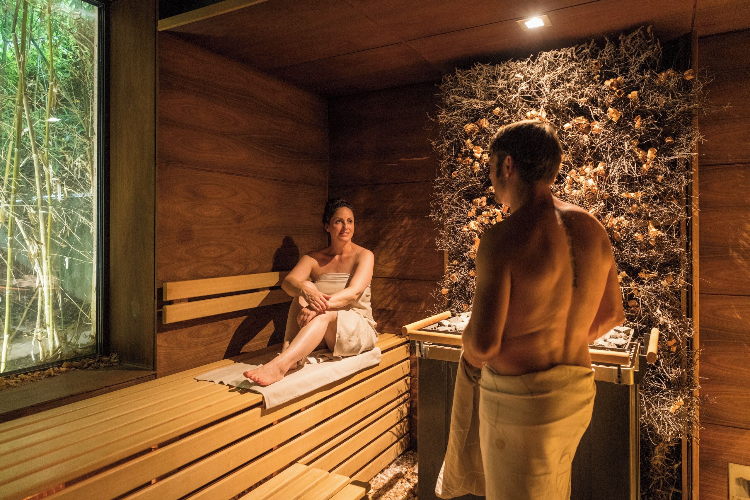 Uma sauna de madeira com bancos e uma parede decorada com ramos e flores.