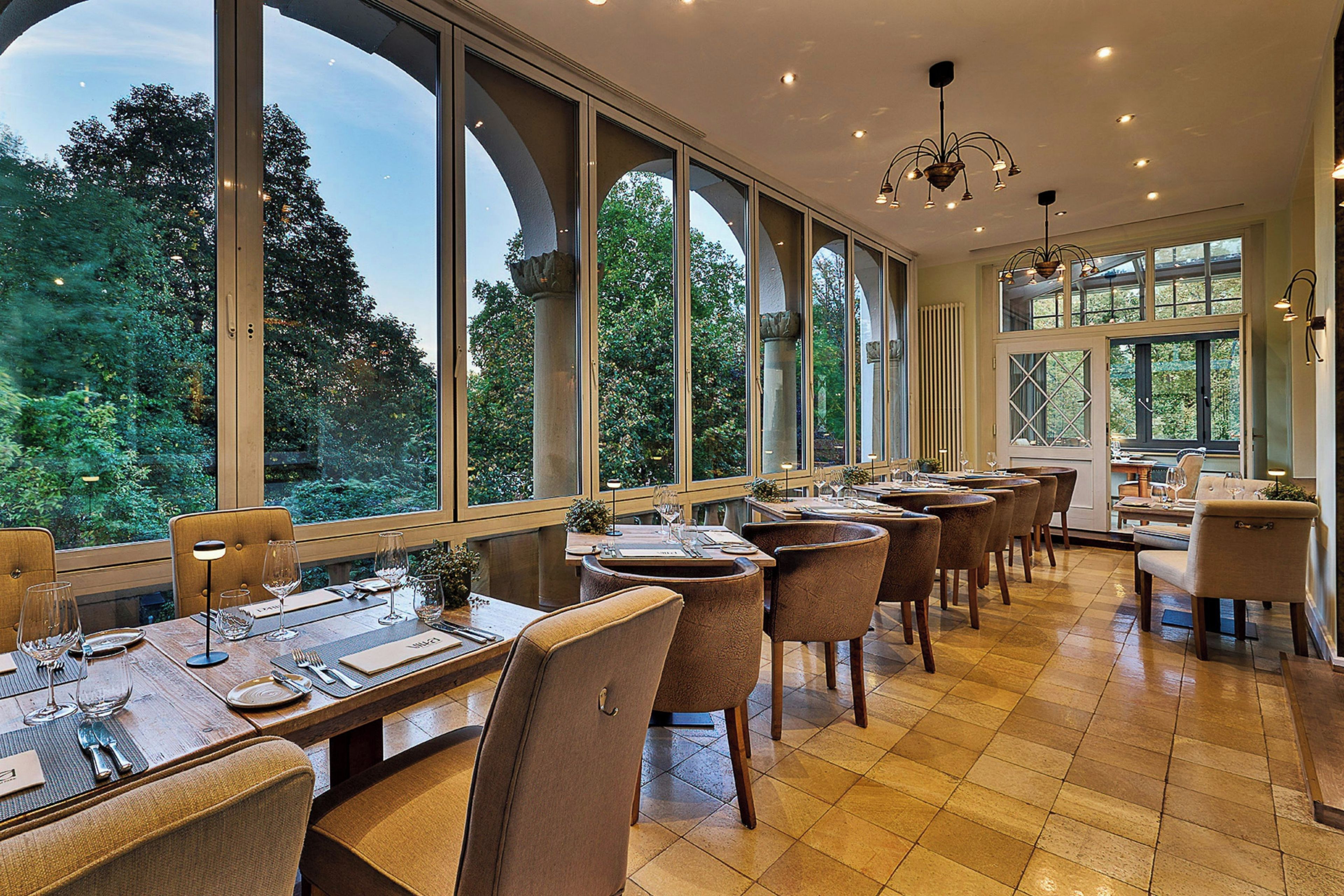 A restaurant with large windows, wooden tables, and chairs.