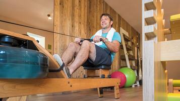 A man using a rowing machine in a room with wooden walls and a wooden floor.