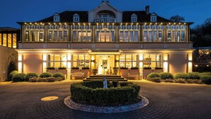 Un hotel amplio y bien iluminado con una entrada imponente, un patio cubierto y un jardín ajardinado con una estatua.