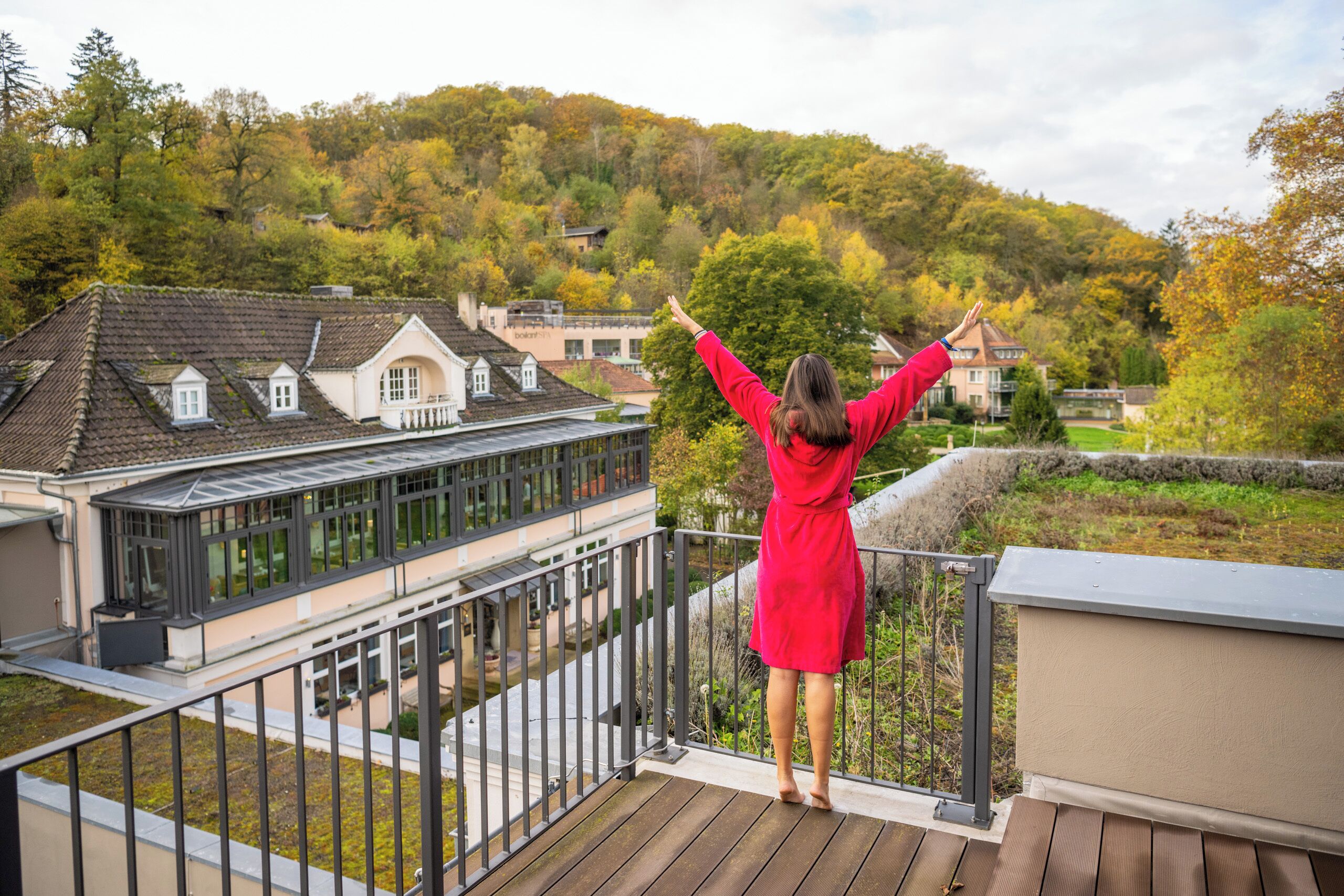 A balcony with a view of a residential area and a house with a sloped roof.
