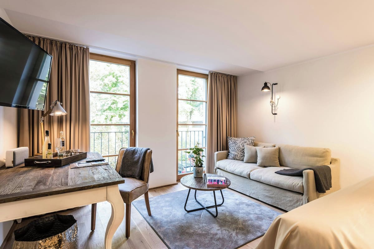 Quarto de hotel moderno com uma mesa de jantar, um sofá, uma mesa de centro e uma televisão.