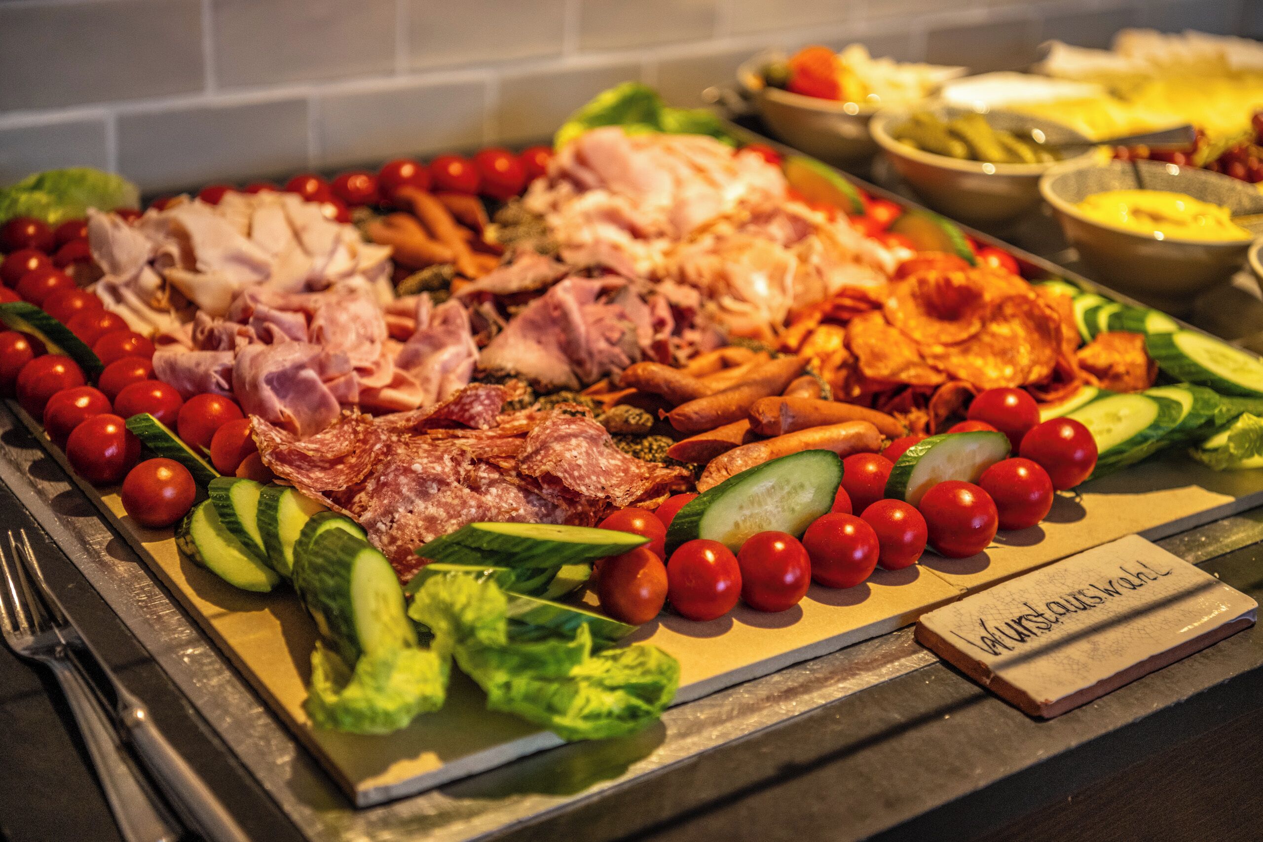 Un bufé con diversas carnes, verduras y un cartel que dice 