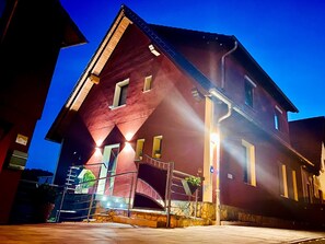 A red building with a steeply pitched roof, multiple windows, and a staircase leading to the entrance.