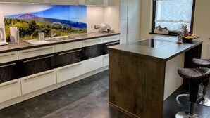 Une cuisine moderne dotée d’un grand îlot central, d’appareils électroménagers en acier inoxydable et d’une fresque murale offrant une vue agréable.
