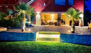 A well-lit patio area with stone flooring, outdoor furniture, and potted plants.