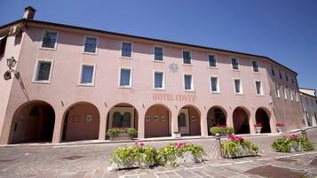 A pink building with the sign "HOTEL CONTA" and arched doorways.