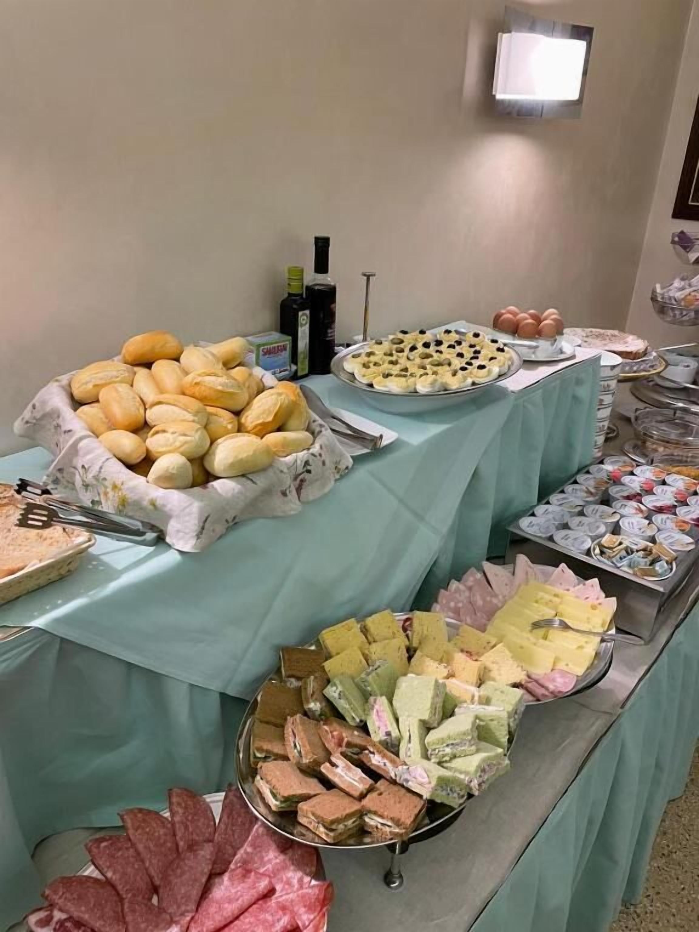 Une table de buffet proposant divers aliments, notamment du pain, des sandwichs et des pâtisseries.
