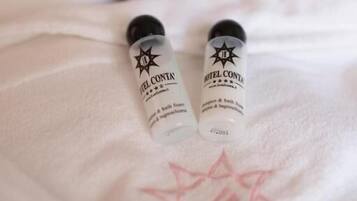 Two bottles of Hotel Conta bath foam on a white towel with a star design.