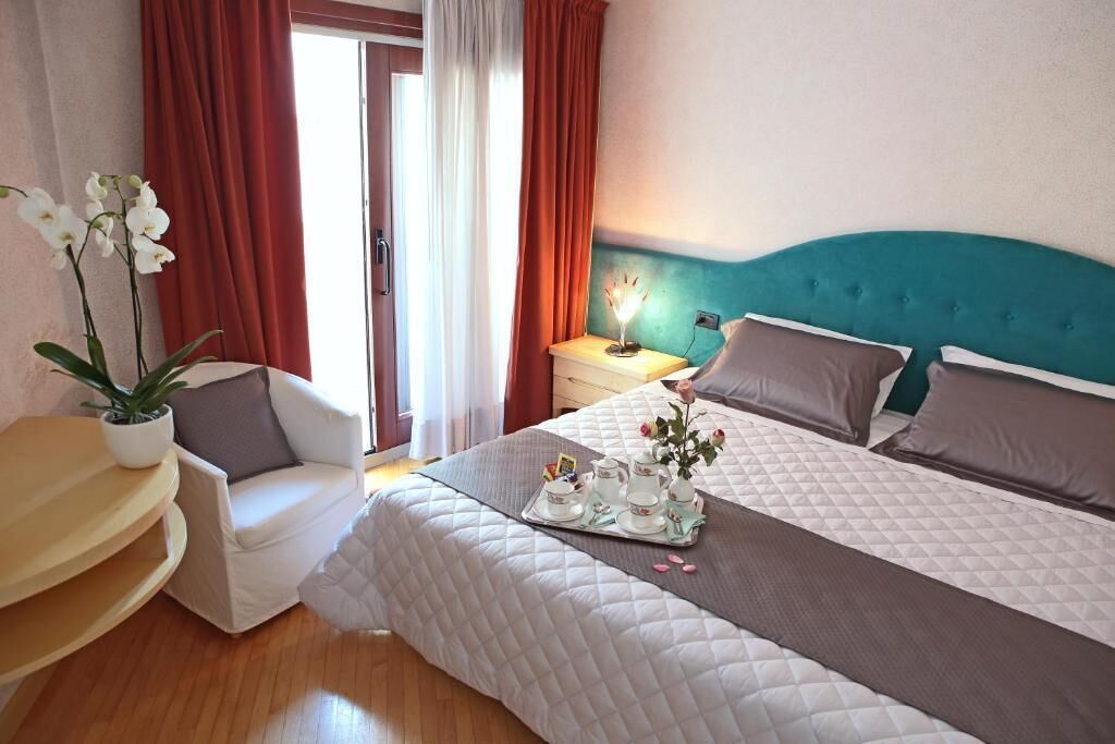 Ein Hotelzimmer mit Bett, Nachttisch, Stuhl und einer Topfpflanze.
