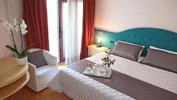Ein Hotelzimmer mit Bett, Nachttisch, Stuhl und einer Topfpflanze.
