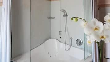 Un baño moderno con bañera de vidrio, ducha e inodoro.