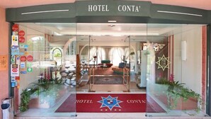 L'entrée de l'hôtel Conta se distingue par une porte en verre, un tapis rouge et une décoration représentant l'Étoile de David.