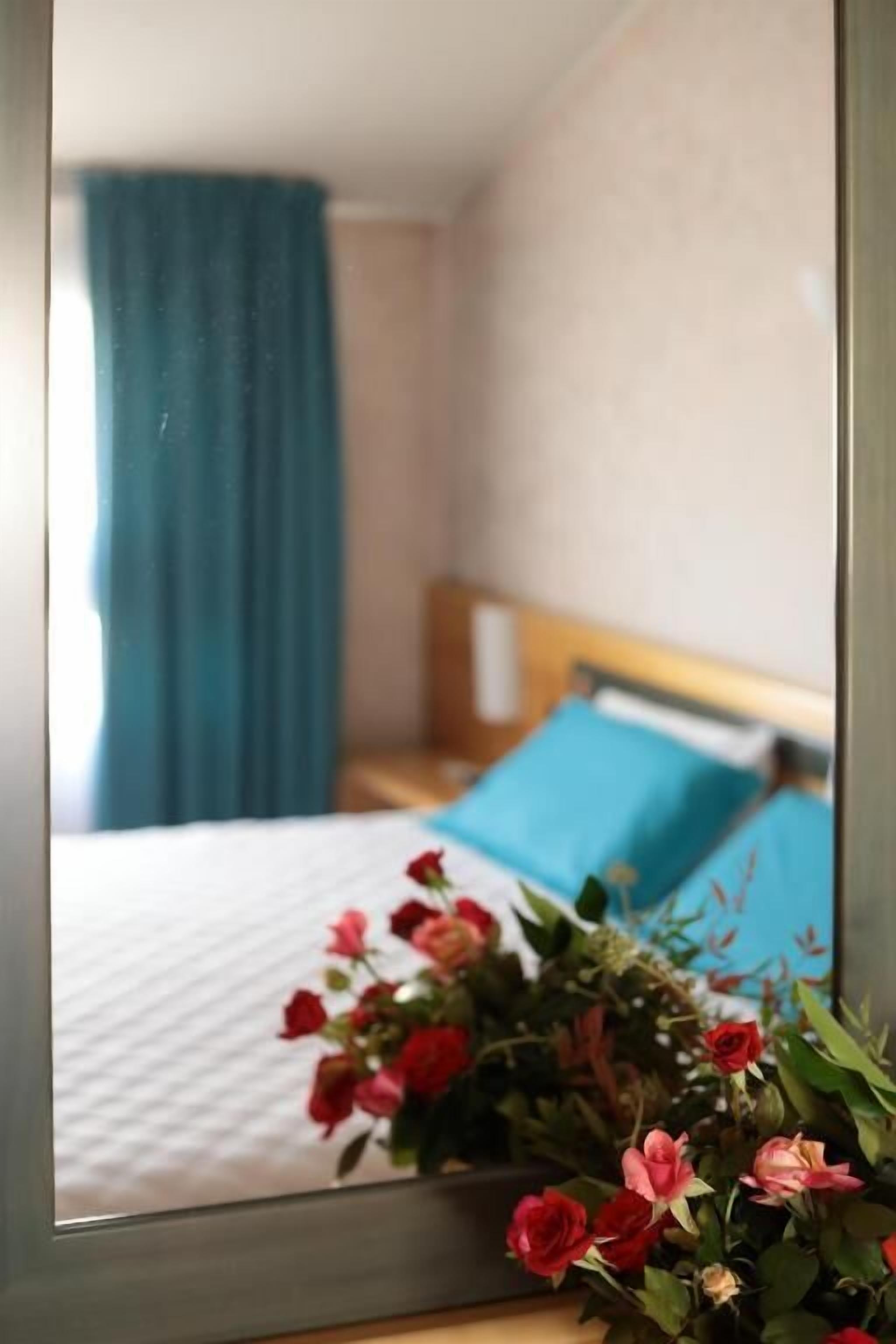 Un dormitorio con una cama, un almohábil azul y un ramo de flores en primer plano.