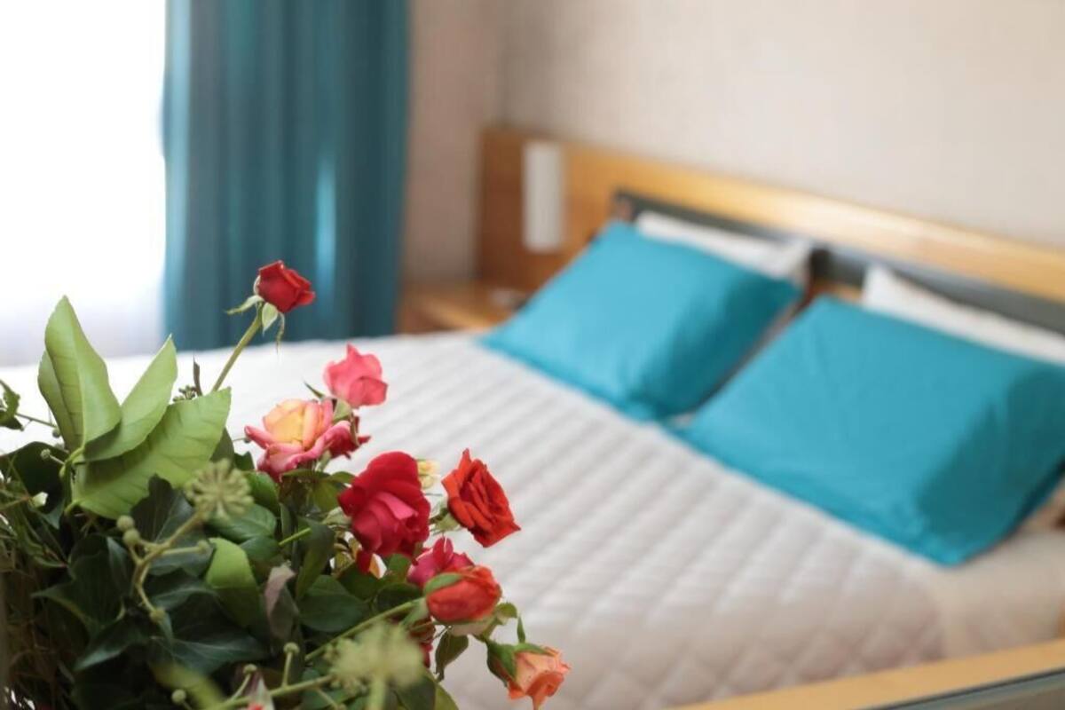 En säng med blå kuddar och en blomsteruppsättning framför.