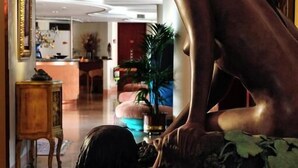 Une sculpture représentant deux personnages, placée dans un hall d’entrée avec un comptoir d’accueil et des plantes en arrière-plan.