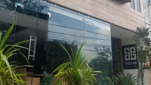 A modern building with a glass entrance, potted plants, and a sign for 'Pride Inn Hotel'. - HOTEL PRIDE INN (Bhopal)