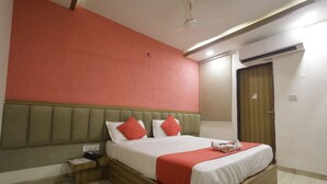 A hotel room with a bed, a nightstand, a telephone, and an air conditioning unit. - HOTEL PRIDE INN (Bhopal)
