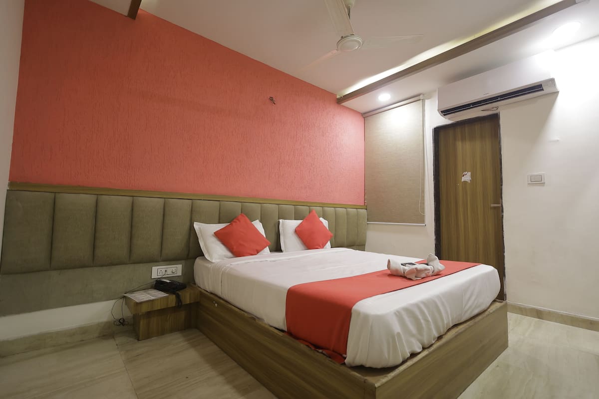 Una habitación de hotel con una cama, una mesita de noche, un teléfono y un equipo de aire acondicionado.