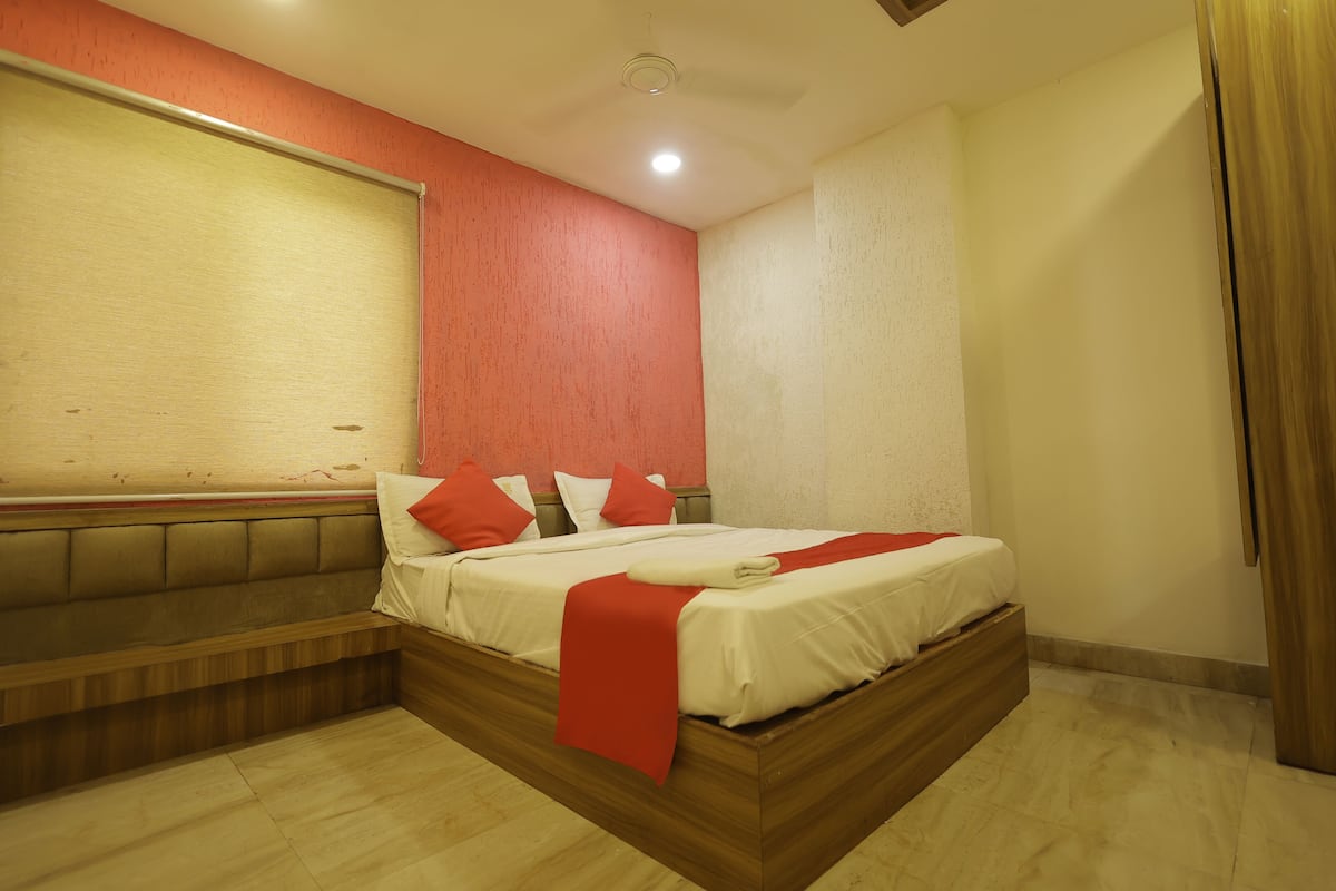 Una habitación de hotel moderna con una cama de madera, un banco y una pared de acento roja.
