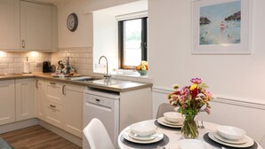 A modern kitchen with white cabinetry, a built-in dishwasher, and a window above the sink. - Primrose at Stancombe Manor, Nr Kingsbridge (Kingsbridge)