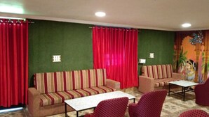 A room with two sofas, a coffee table, and red patterned chairs. - Shivas Heritage and Sand Dunes (Jaisalmer)