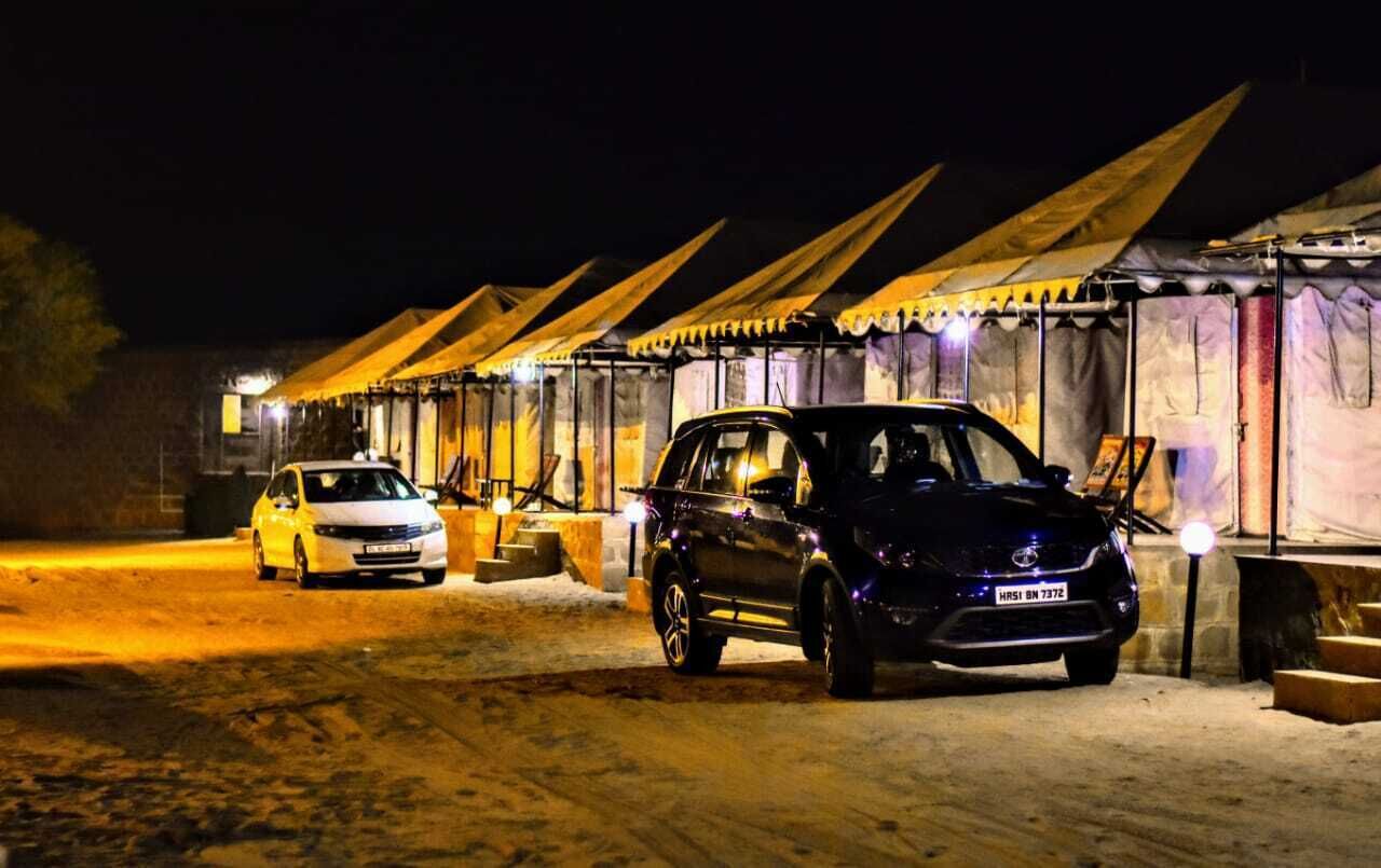 A row of tents with a black SUV parked in front.