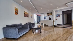 A modern hotel lobby with a reception desk, sofas, and artwork on the walls. - Hotel Grand View (Kathmandu)
