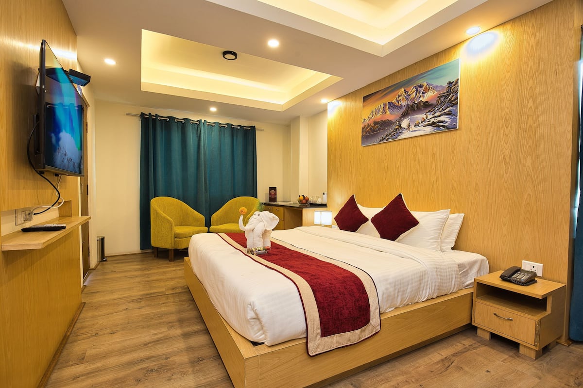 A hotel room with a bed, a TV, a desk, and a chair.