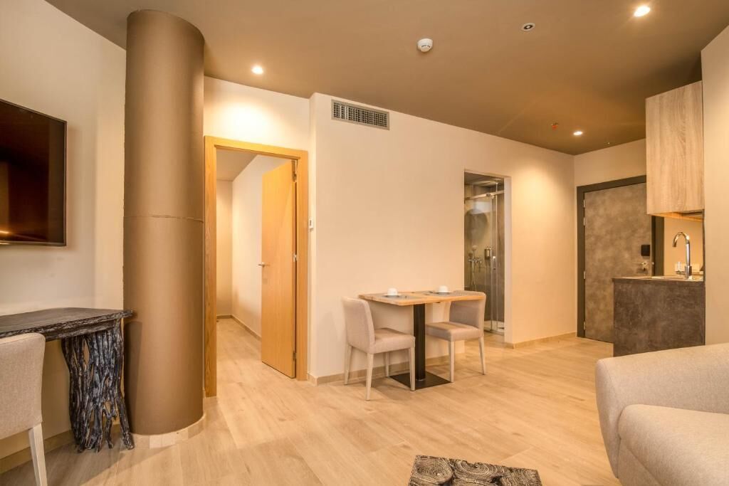A modern living room with a wooden table, a sofa, and a large pillar.