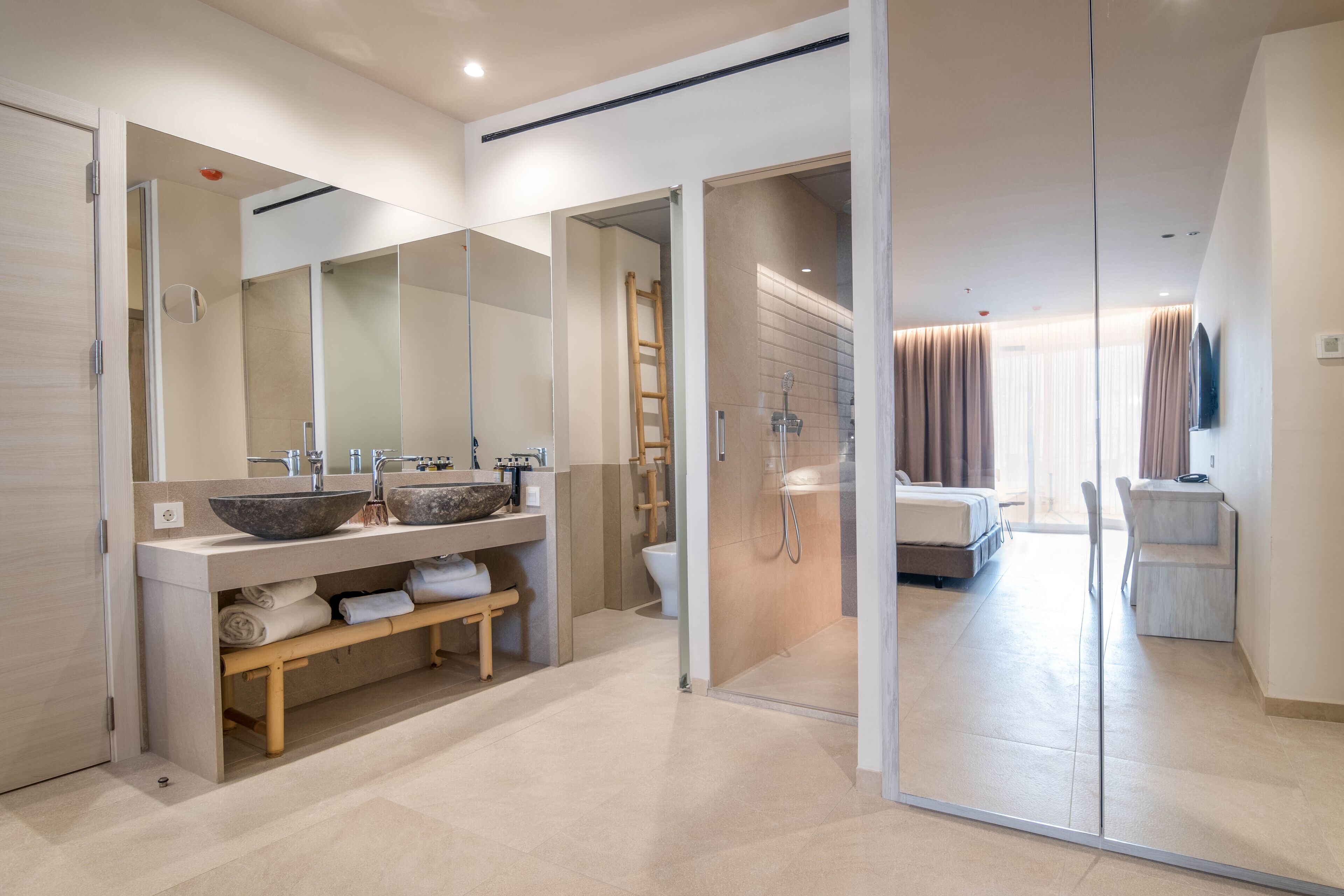 A modern bathroom with a large mirror, dual sinks, and a shower area.