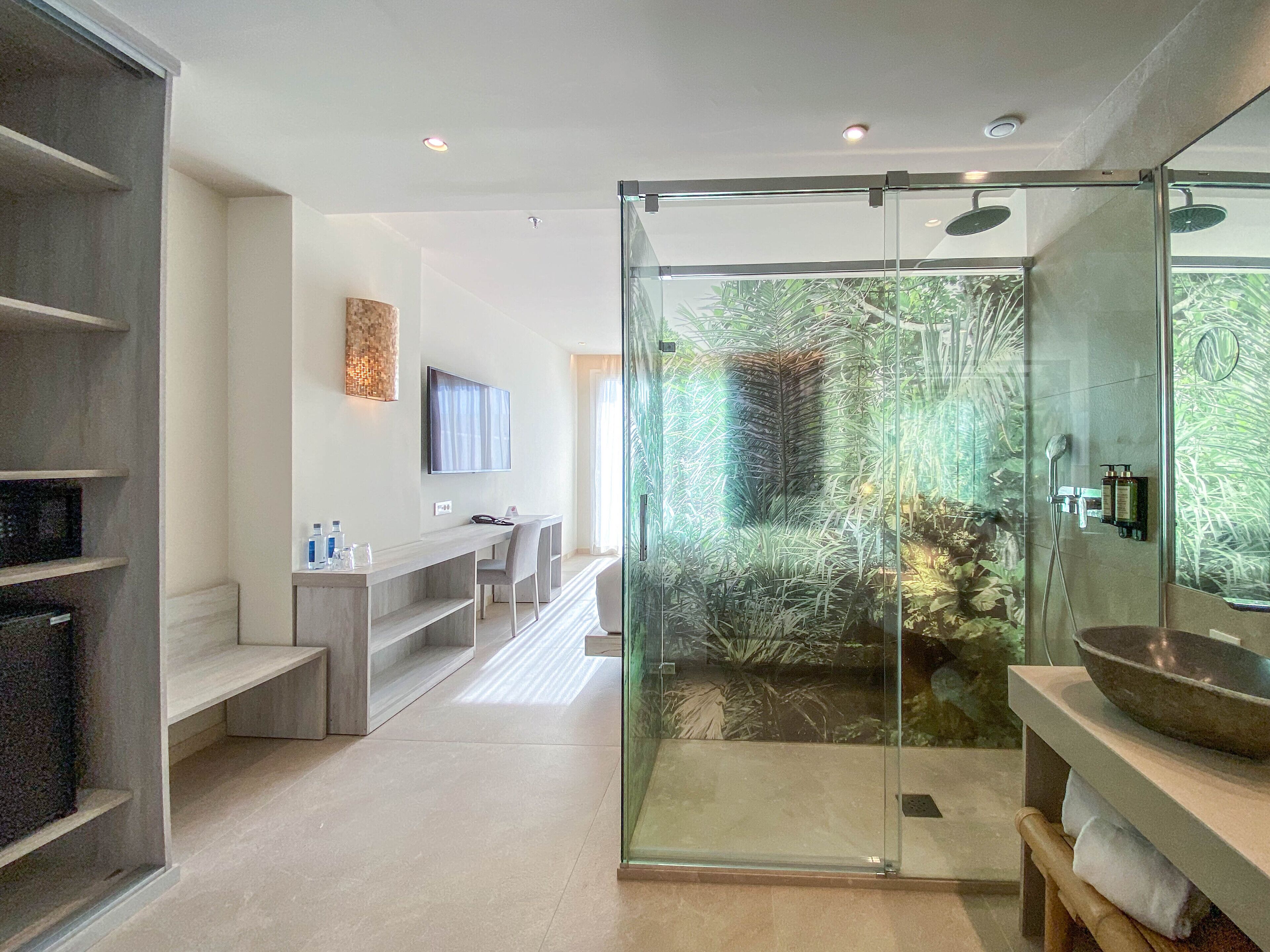 A modern bathroom with a glass-enclosed shower, a large mirror, and a wooden vanity.