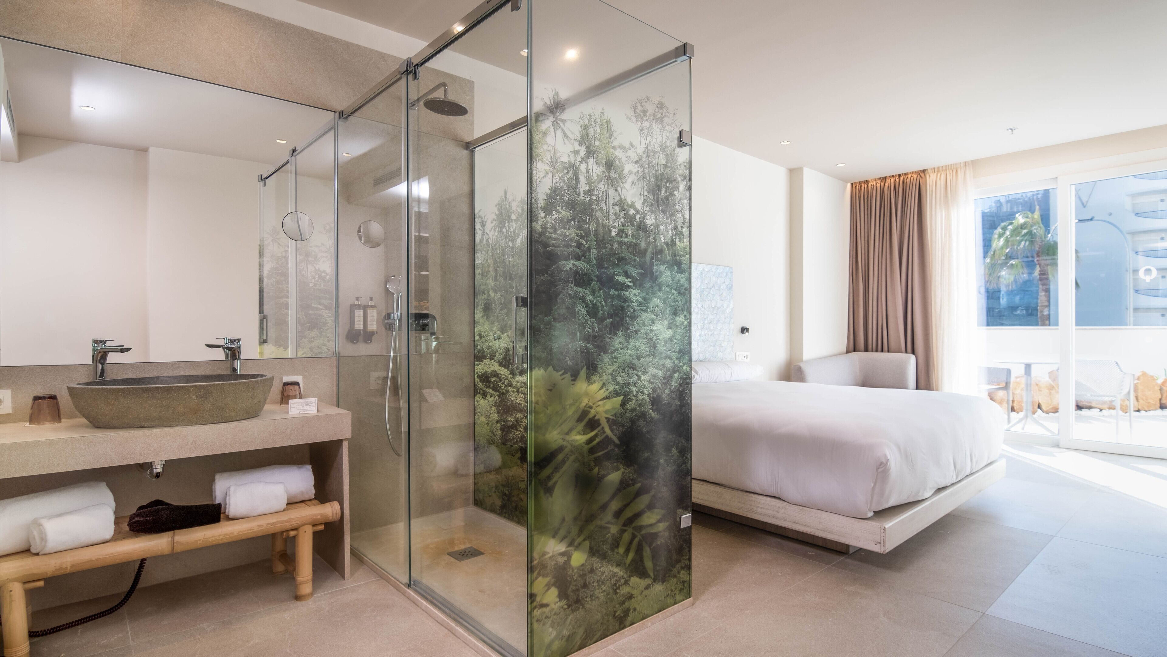 A modern bathroom with a glass shower enclosure, a large sink, and a bench.