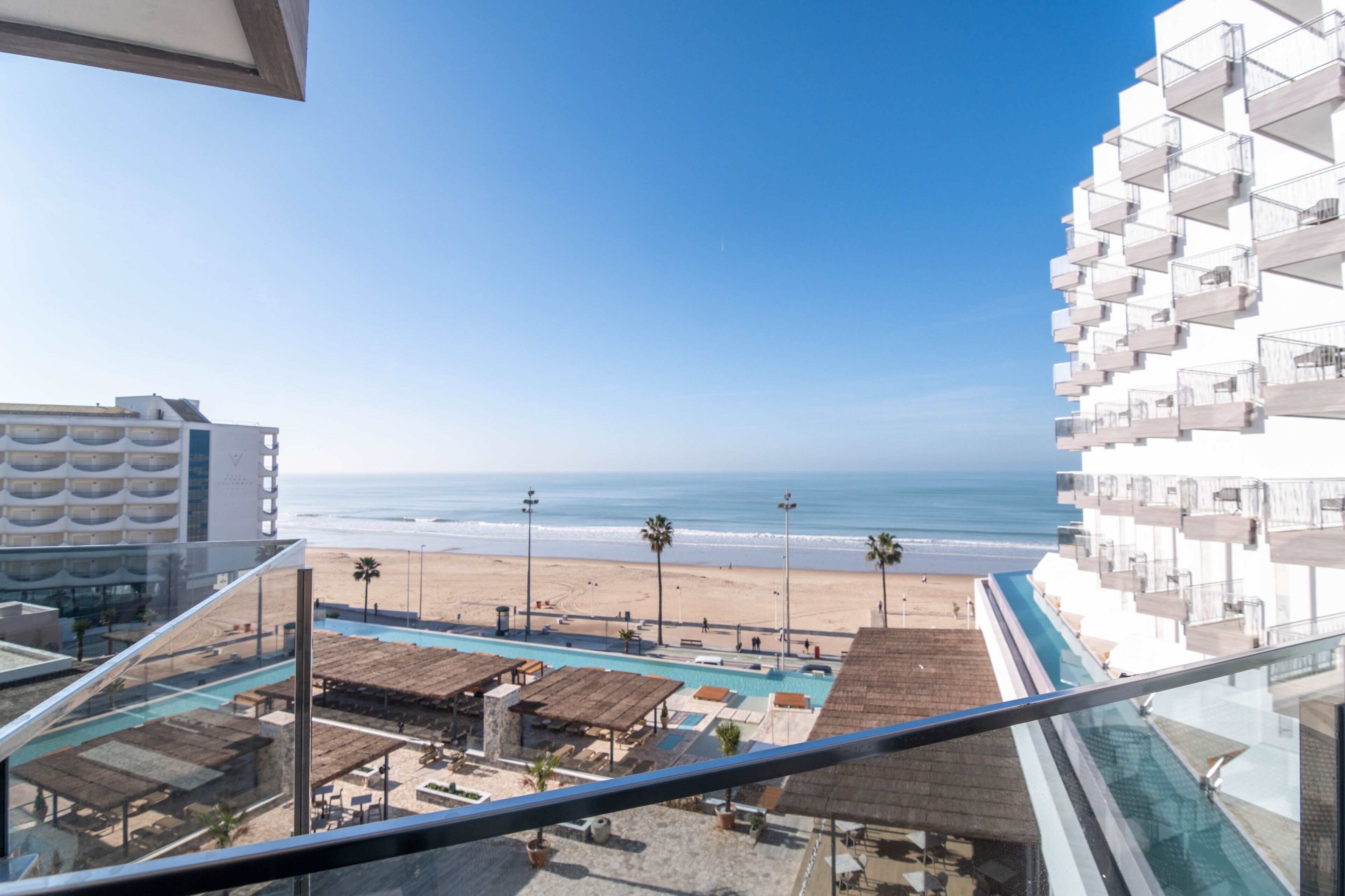 Vista dal balcone di un hotel sulla spiaggia, sulla piscina e sull'oceano.
