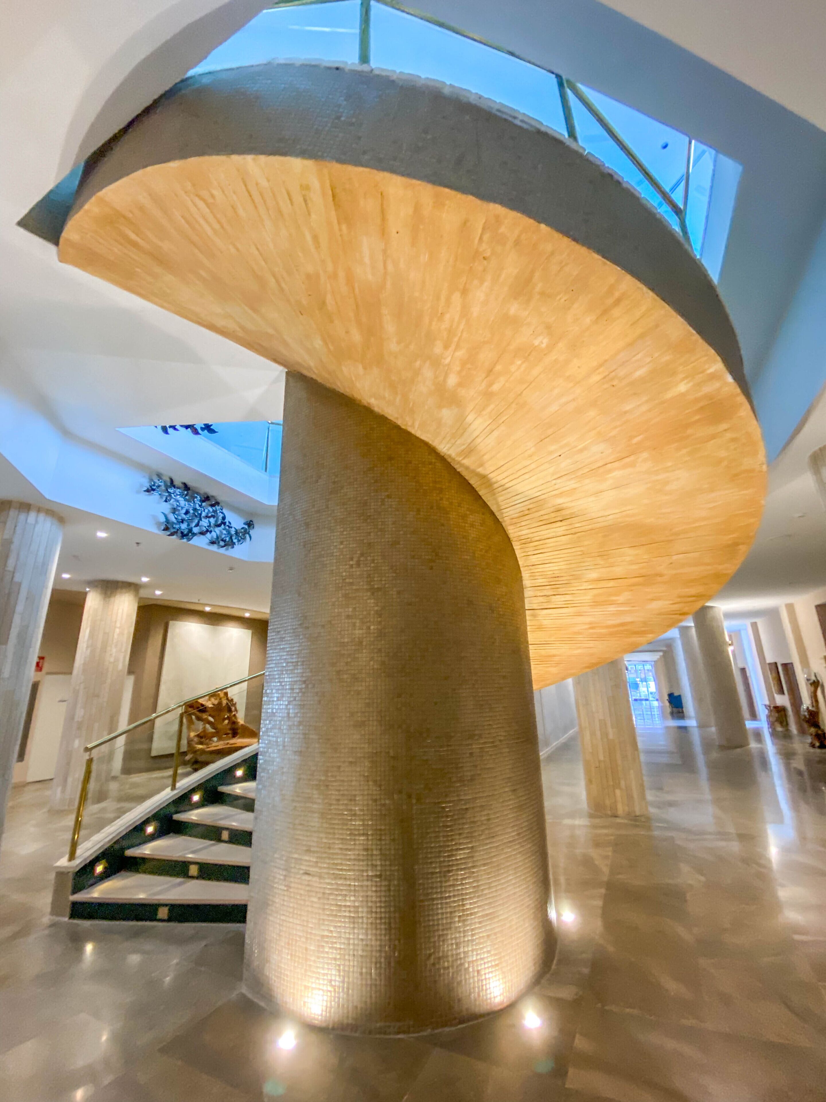 Un interior moderno con una columna metálica central y una escalera de caracol.